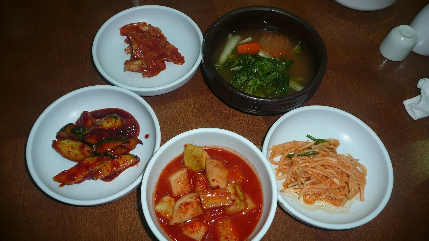 Plates of fermented foods including kimchi, pickled radish and cucumber